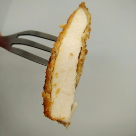 Bocado de milanesa de pollo cocida tenedor con una porcion de milanesa de pollo